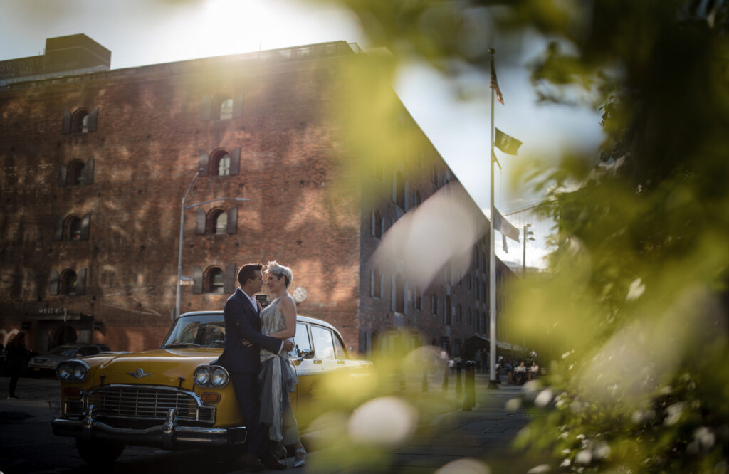 A bride and groom elopement in front of a yellow car at Brooklyn Bridge Park.