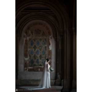 A bride in a wedding dress standing in front of an archway at Central Park during her elopement.