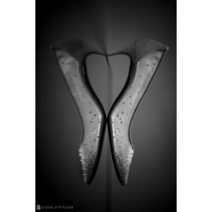 Black and white photograph of a pair of high heeled shoes at a wedding.