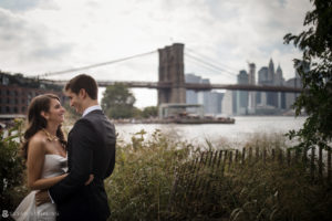Wedding couple standing in front of the Brooklyn Bridge.