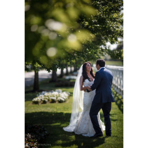 A bride and groom hugging on their wedding day in the grassy fields of Bridgehampton, New York.