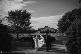 A black and white photo of a bride and groom standing in front of a house in Bridgehampton, New York.