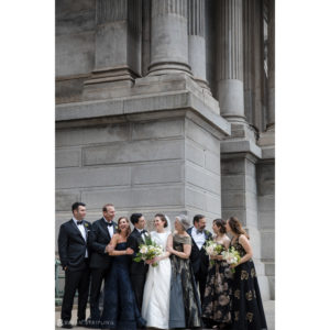 A group of bridesmaids and groomsmen posing in front of the Westin building in Philadelphia.