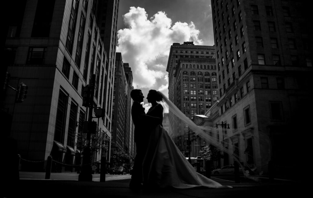 A bride and groom kiss during their wedding at the Westin in Philadelphia, with tall buildings forming an enchanting backdrop.