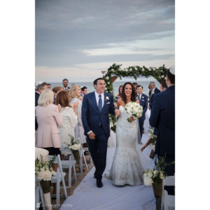 A New York couple celebrating their wedding in Bridgehampton, joyfully walking down the aisle at a picturesque beach ceremony.