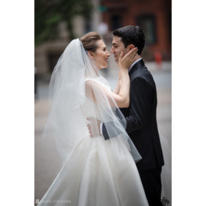 A bride and groom sharing a passionate kiss in front of the Westin building during their Philadelphia wedding.