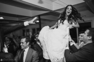 In Bridgehampton, New York, a bride is being carried by a group of people at a wedding.