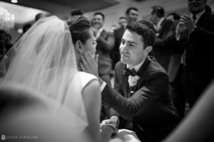 A bride and groom sharing a passionate kiss at their luxurious wedding at the Westin in Philadelphia, surrounded by an adoring crowd.