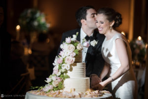 A wedding couple kissing in front of their wedding cake at the Westin in Philadelphia.