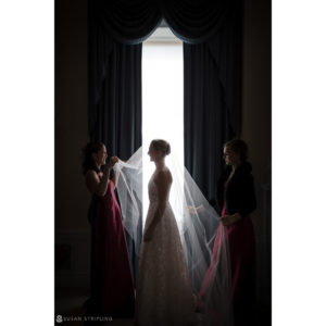 Three bridesmaids standing in front of a window at a wedding.
