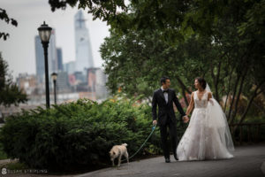 A Tribeca wedding with the bride and groom walking their dog in a park, with the city skyline in the background.