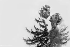 A black and white photo capturing a couple's intimate kiss in front of a tree on their wedding day at the Sleepy Hollow Country Club.