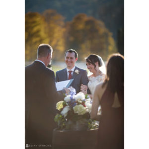 A bride and groom smiling at each other during their fall wedding at Riverside Farm.