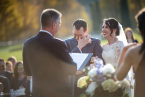 A bride and groom laughing during their Fall wedding ceremony at Riverside Farm.