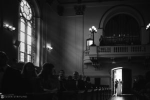 A bride and groom exchanging vows in the aisle of a church during their wedding at Sleepy Hollow Country Club.