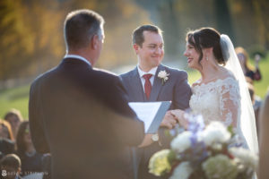 A bride and groom laughing during their Riverside Farm wedding ceremony.