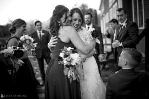 A bride is hugging her bridesmaids at their riverside farm wedding.