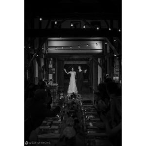 A black and white photo of a bride and groom in Riverside Farm, a barn, during their fall wedding.