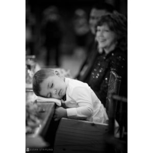 A little boy is peacefully sleeping at a fall wedding by Riverside Farm.