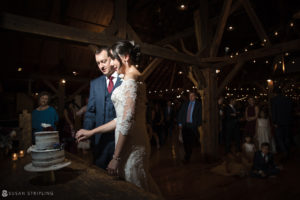 A fall wedding at Riverside Farm, with the bride and groom cutting a cake in a barn.