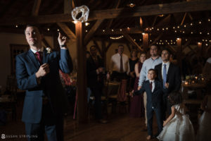 A man in a suit is holding up a ring at a wedding reception at Riverside Farm.