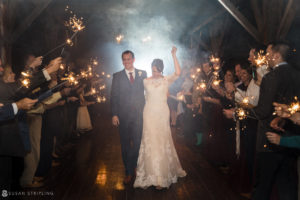 A Fall wedding at Riverside Farm, where a bride and groom are exiting a barn amidst sparklers.