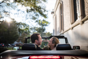 A bride and groom enjoying their wedding day in the back of a convertible car at Sleepy Hollow Country Club.