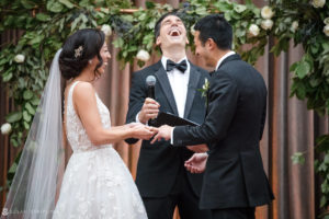 A bride and groom laughing during their rooftop wedding ceremony.
