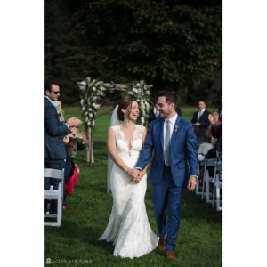 A riverside farm wedding with a bride and groom walking down the aisle at an outdoor ceremony.