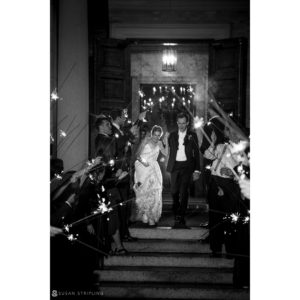 A wedding couple gracefully walks down the steps of Sleepy Hollow Country Club, surrounded by enchanting sparklers.