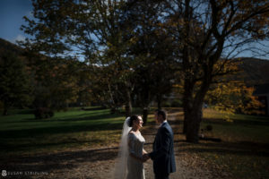 A fall wedding at Riverside Farm, with the bride and groom standing on a path surrounded by beautiful autumn foliage.