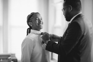 A man putting a tie on a young man at a wedding.