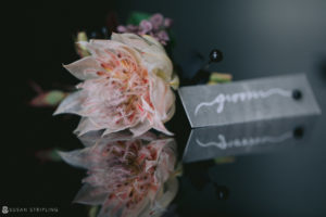 At a wedding reception at 501 Union, a flower delicately sits on a table next to a name card.