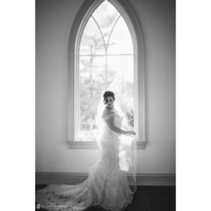 A bride posing in front of a window at Park Chateau for her wedding.