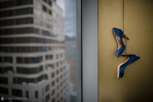 A pair of blue wedding shoes hanging from a Battery Gardens window.