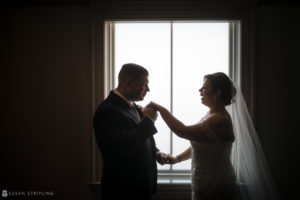 A bride and groom at Park Chateau, standing in front of a window.
