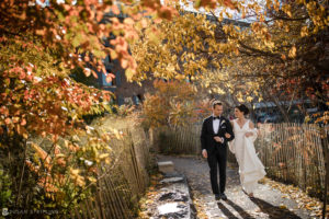 A wedding couple walking down a path in Battery Gardens in the fall.