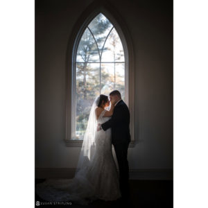 A Park Chateau wedding with a bride and groom embracing in front of a window.