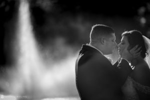 A Wedding bride and groom kiss in front of a Park Chateau fountain.