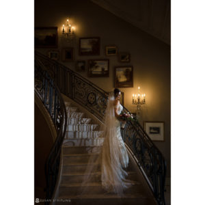 A bride standing on a staircase at Park Chateau's wedding venue.