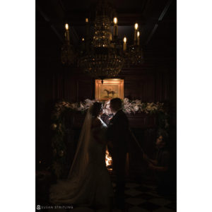 A wedding couple kiss in front of a fireplace at Park Chateau.