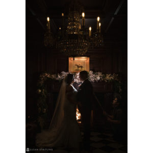 A bride and groom kiss at their wedding in front of a fireplace at Park Chateau.