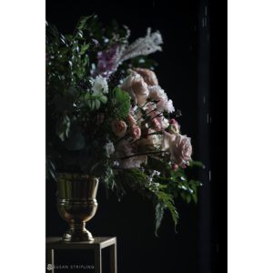A bouquet of flowers in a gold vase on a wedding table.