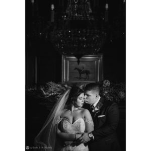 A bride and groom embracing in front of a chandelier at their elegant Park Chateau wedding.