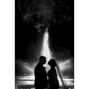 A wedding couple standing in front of the Park Chateau fountain.