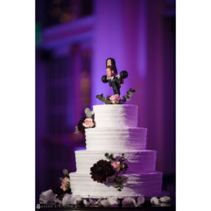 A white Park Chateau wedding cake with a figurine on top.