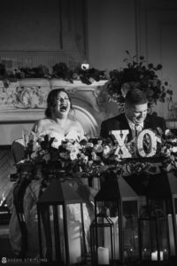 A Park Chateau wedding where a bride and groom are laughing in front of a fireplace.