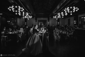 A black and white photo of a wedding couple dancing in a dark room at 501 Union.