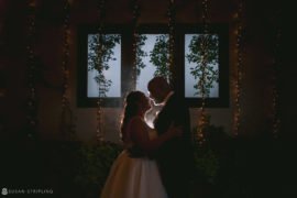 A bride and groom embracing in front of a window at their wedding at 501 Union.