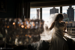 A bride in a wedding dress standing in front of a window at a private club in Manhattan.